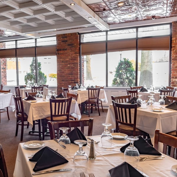 Ciro's Italian restaurant dining room with set tables, white tablecloths, and large windows.