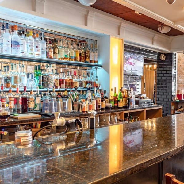 A well-stocked bar at Ciro's with various liquor bottles, bar tools, and a dark granite countertop.