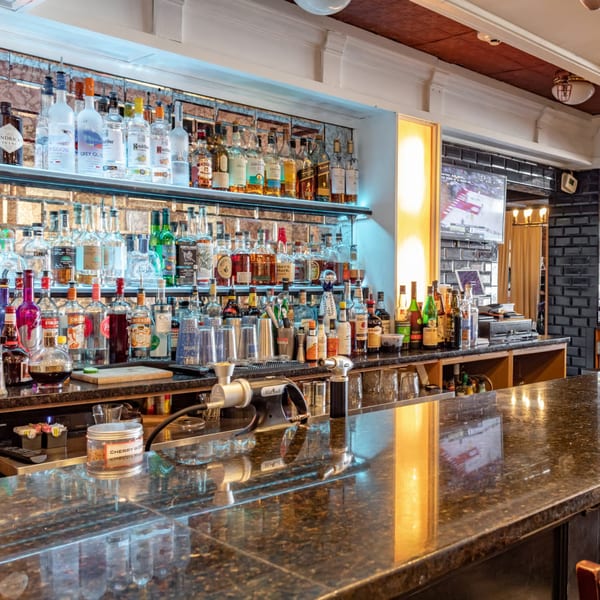 A well-stocked bar at Ciro's with numerous liquor bottles, bar tools, and a dark granite countertop.