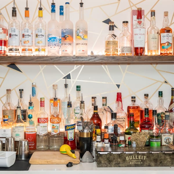 A well-stocked bar at Ciro's, featuring various liquor bottles, bar tools, and a wooden cutting board.
