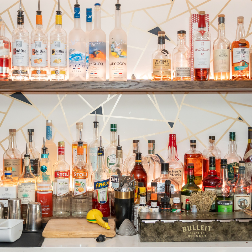 A well-stocked bar at Ciro's, featuring various liquor bottles, bar tools, and a wooden cutting board.