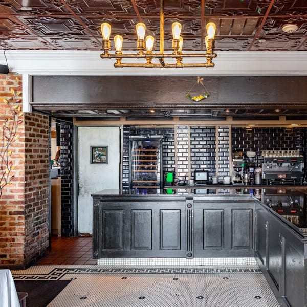 Ciro's bar area with a wine cooler, espresso machine, and black tiled walls.