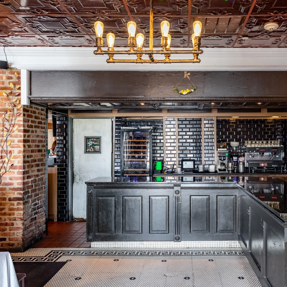 Ciro's bar area with a wine cooler, espresso machine, and black tiled walls.